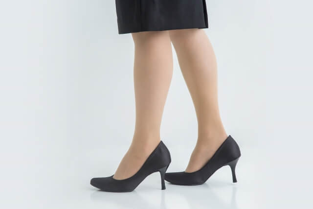 スーツに黒いパンプスを履いている女性の脚