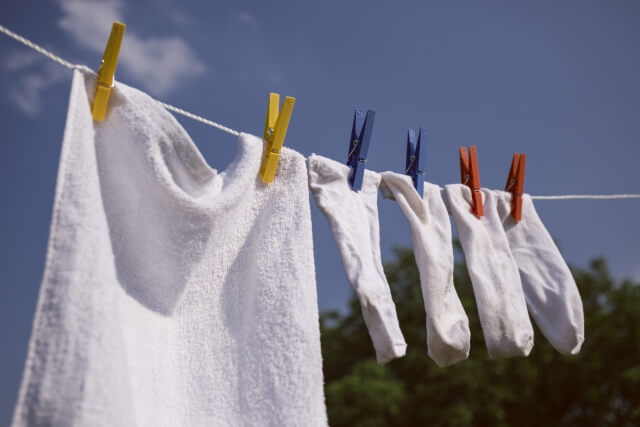 青空の下で干されている白いタオルと白い靴下の洗濯物